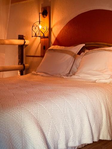 Un dormitorio con una cama blanca con cabecero de madera. en Le mazet du cavalier, en Puyvert