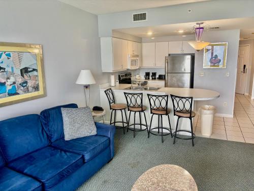 a living room with a blue couch and a kitchen at Ocean Walk Resort - Breathtaking Ocean Front View in Daytona Beach