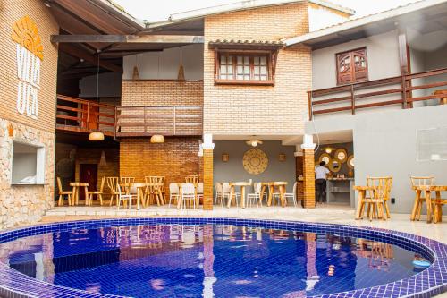 a swimming pool in front of a building with tables and chairs at Pousada Villa Uçá Frances - Praia do Frances in Marechal Deodoro