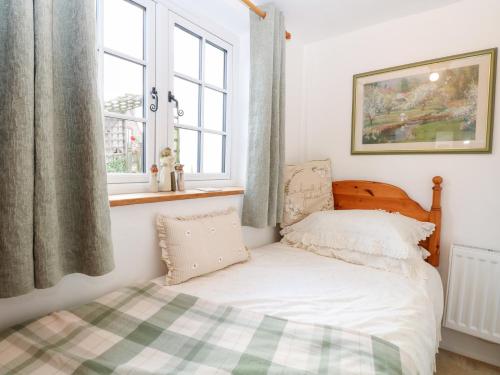 een kleine slaapkamer met een bed en een raam bij Hollyhedge Cottage in Briston