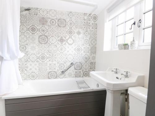 een badkamer met een ligbad en een wastafel bij Hollyhedge Cottage in Briston