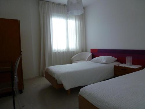 a hotel room with two beds and a window at Hotel Villa Selva in Lugano