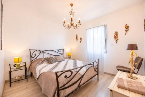 a bedroom with a bed and a chandelier at La Maison du Payré - 2 personnes in Talmont