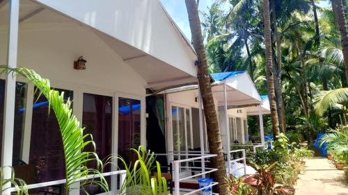 a white house with palm trees in front of it at CSF Boutique Homestay in Palolem