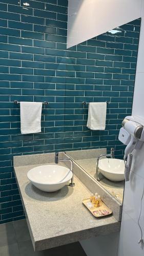 a blue tiled bathroom with two sinks and towels at POUSADA ESTÂNCIA in Penedo