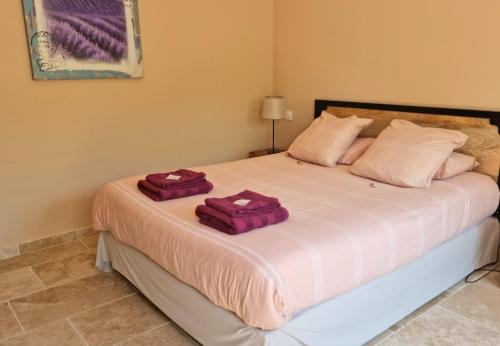 a bedroom with a large bed with purple towels on it at L'eden Provençal in Les Saquetons