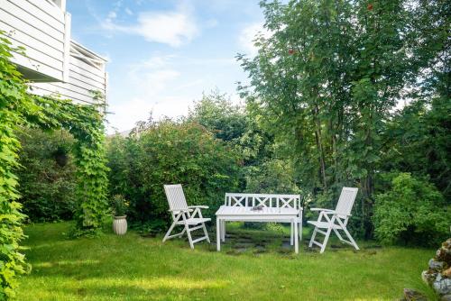 two white chairs and a table in a yard at Boukersen Heim in Tromsø