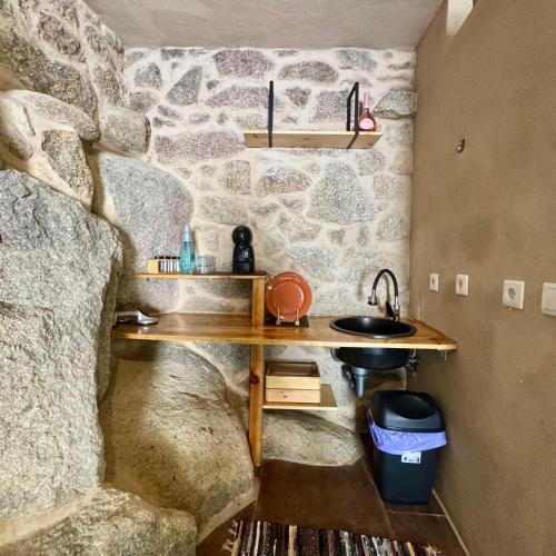 a bathroom with a stone wall and a sink at Gardunha Stone in Louriçal do Campo