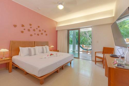 a bedroom with a bed and a desk and a television at Palmar del Sol by Riviera Maya Suites in Playa del Carmen