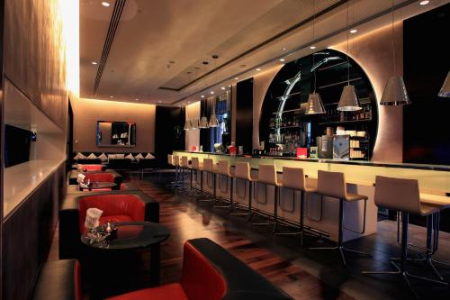 a restaurant with a bar with red chairs at Yas Plaza Circuit by IHG in Abu Dhabi