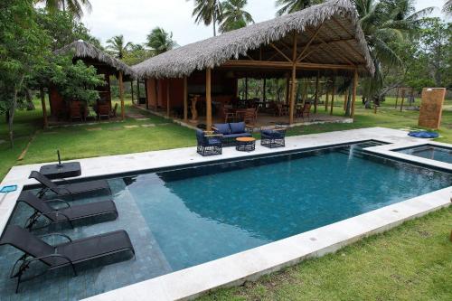a swimming pool with chairs and a house at Chalé Iracema - Cond Villa Igarapé- Atins in Barreirinhas