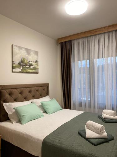 a bedroom with a bed with green pillows and a window at Apartman Kristal, Vrnjačka Banja in Vrnjci