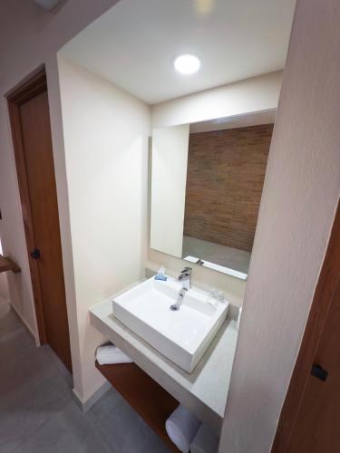 a bathroom with a white sink and a mirror at Kooch Aparthotel in Oaxaca City