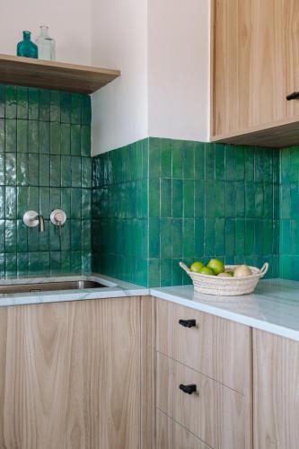 a kitchen with green tiled walls and a bowl of fruit at Can Bo in Villajoyosa