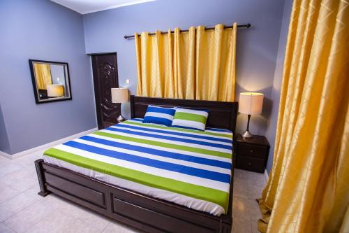 a bedroom with a bed with a colorful striped bedspread at Rapid City Guest House Accra in Oshiyie