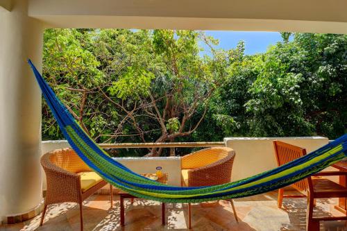 a hammock on a patio with chairs and trees at Palmar del Sol by Riviera Maya Suites in Playa del Carmen