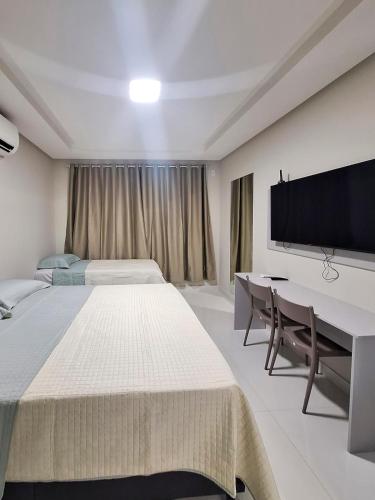 ein Schlafzimmer mit zwei Betten und einem Schreibtisch und einem Fernseher in der Unterkunft Studio 14 - 2K Atalaia Apenas 150m da Orla in Aracaju