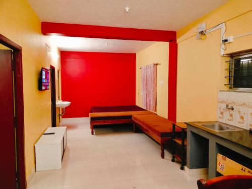 a room with a red wall with a bench in it at Harvest Hill View Cottage in Ooty