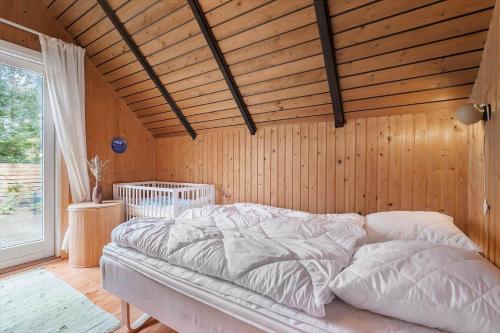 a bed in a room with a wooden wall at 80179-Vemb-Harpotvej-74 in Skalstrup