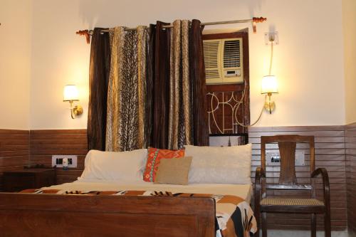 a bedroom with a bed with a window and a chair at Kolkata Vintage Stay - 2BHK with Bengali Home Vibe in Kolkata