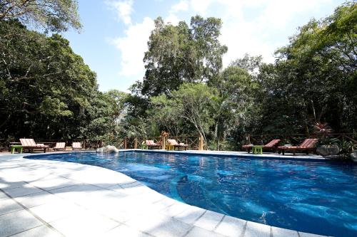 a swimming pool in a yard with chairs and trees at Hotel Jungle Lodge Tikal in Tikal