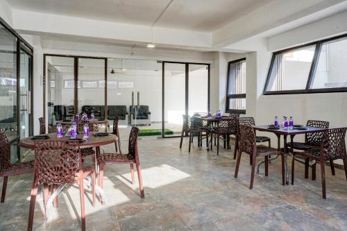 a dining room with tables and chairs and windows at Collection O Golden Leaf in Pune