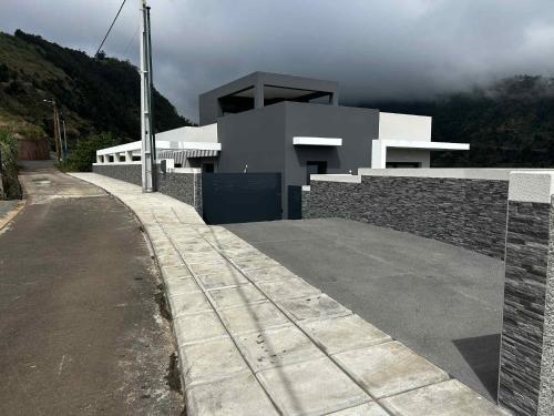 a white house with a stone wall next to a street at The Barreto's Clive in Ponta do Sol