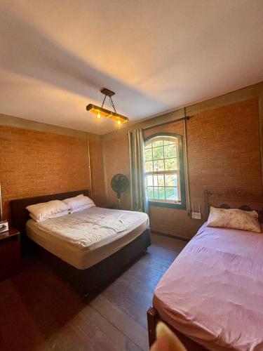 ein Schlafzimmer mit zwei Betten und einem Fenster in der Unterkunft Chalé em Conceição do Ibitipoca in Lima Duarte