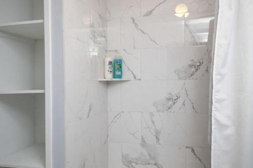 a bathroom with white marble walls and a shower at 4th St Little Blue in Bham in Graymont