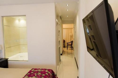 Un dormitorio con un televisor de pantalla plana en una pared. en Argentino Hotel, en Mar del Plata