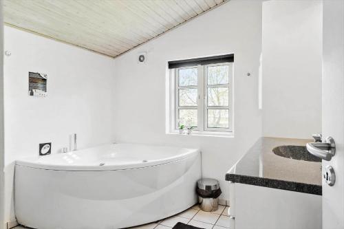a white bathroom with a large tub and a window at 20712-Ulfborg-Knakvej-36 in Vedersø Klit