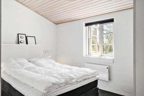 a white bedroom with a large bed and a window at 20712-Ulfborg-Knakvej-36 in Vedersø Klit