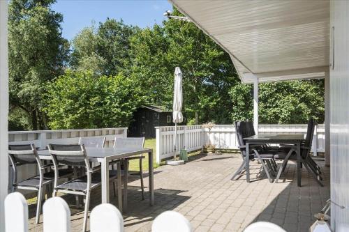 a patio with tables and chairs and an umbrella at 30401-Ulfborg-Klovervej-469 in Vang