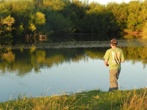 a man standing in front of a body of water at Alquimia Posada in Guichón