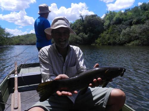 a man sitting in a boat holding a fish at Alquimia Posada in Guichón