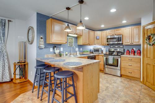 a kitchen with wooden cabinets and a island with bar stools at Foxes Den with Hot Tub, Pool Table and Fire Pit! in Troy