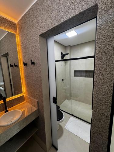 a bathroom with a glass shower and a sink at Grande Hotel in Gurupi