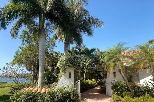 a palm tree in front of a white house at Paradise with a pool, pier and private beach area in Osprey