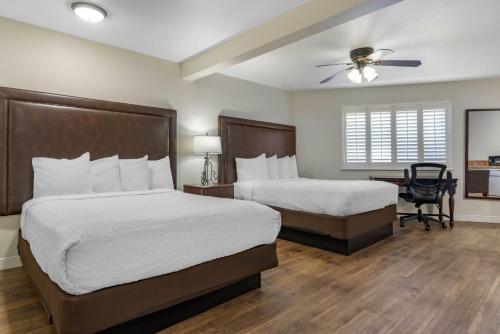 a bedroom with two beds and a desk and a ceiling fan at Best Western Rose Garden Inn in Watsonville