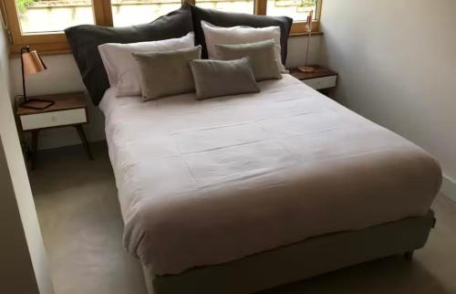 a large bed with white sheets and pillows in a room at Ravissant appartement vue lac Lutry Lausanne avec terrasse in Arni Alp