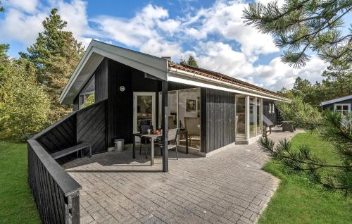 a black house with a patio with a table at Stunning Home In Fjerritslev With Sauna in Fjerritslev
