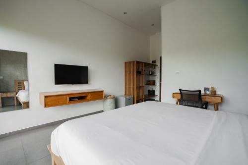 a bedroom with a bed and a tv on a wall at Suksma Guesthouse in Canggu