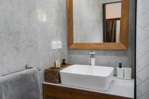 a bathroom with a white sink and a mirror at Suksma Guesthouse in Canggu