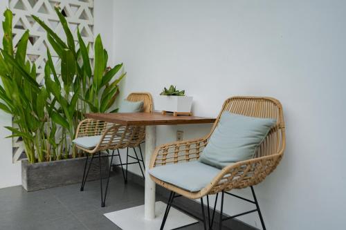 two wicker chairs and a wooden table in a room with plants at Suksma Guesthouse in Canggu