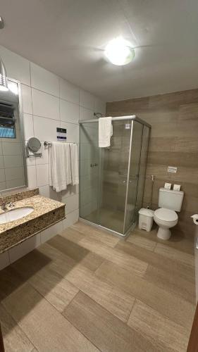 a bathroom with a glass shower and a toilet at Hotel Fazenda Vilarejo All Inclusive in Conservatória