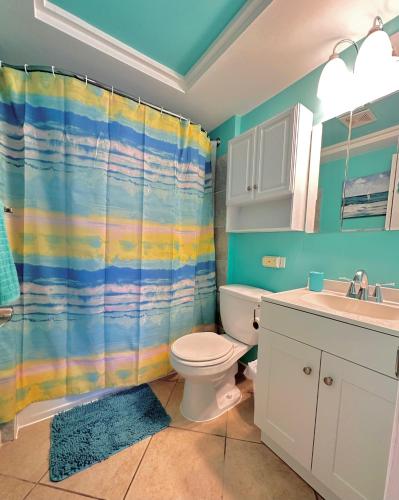 a bathroom with a rainbow shower curtain and a toilet at atlantic terrace pompano beach #1 in Pompano Beach