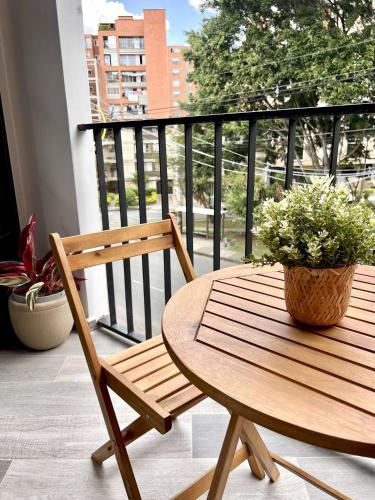 a wooden chair and a table with a potted plant on a balcony at BIT by Simple stay in Medellín