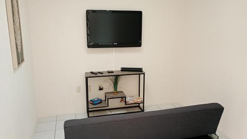 a tv on a wall next to a couch at Casa Alcatraz con Alberca, Cuernavaca Morelos in Tezoyuca