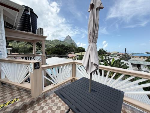 an umbrella on a balcony with a view of a mountain at Maggie's Inn in Soufrière