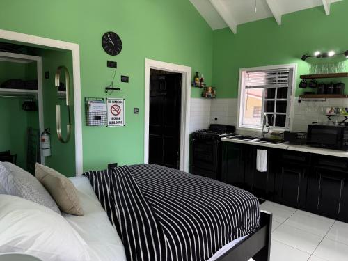 a green room with a bed and a kitchen at Maggie's Inn in Soufrière